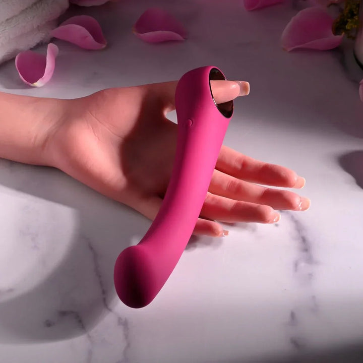 Evolved Pleasure Curve in Pink lying across an open hand on marble, rose petals scattered