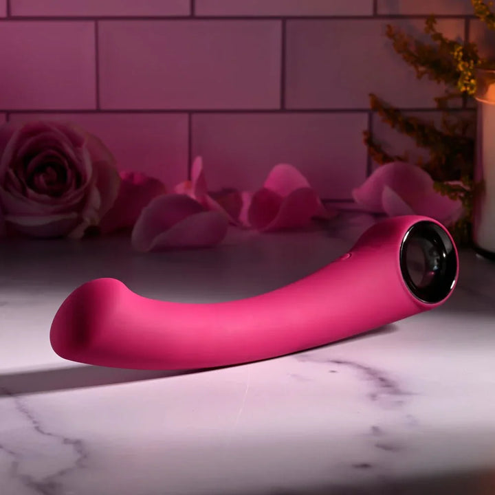 Evolved Pleasure Curve in Pink lying flat with the chrome ring handle to the right