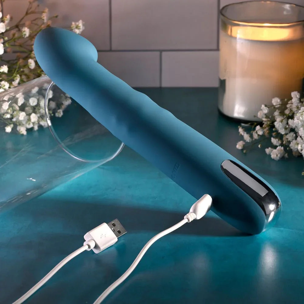 Evolved Queen Of All Trades in teal blue with its white USB charging cable plugged into the handle