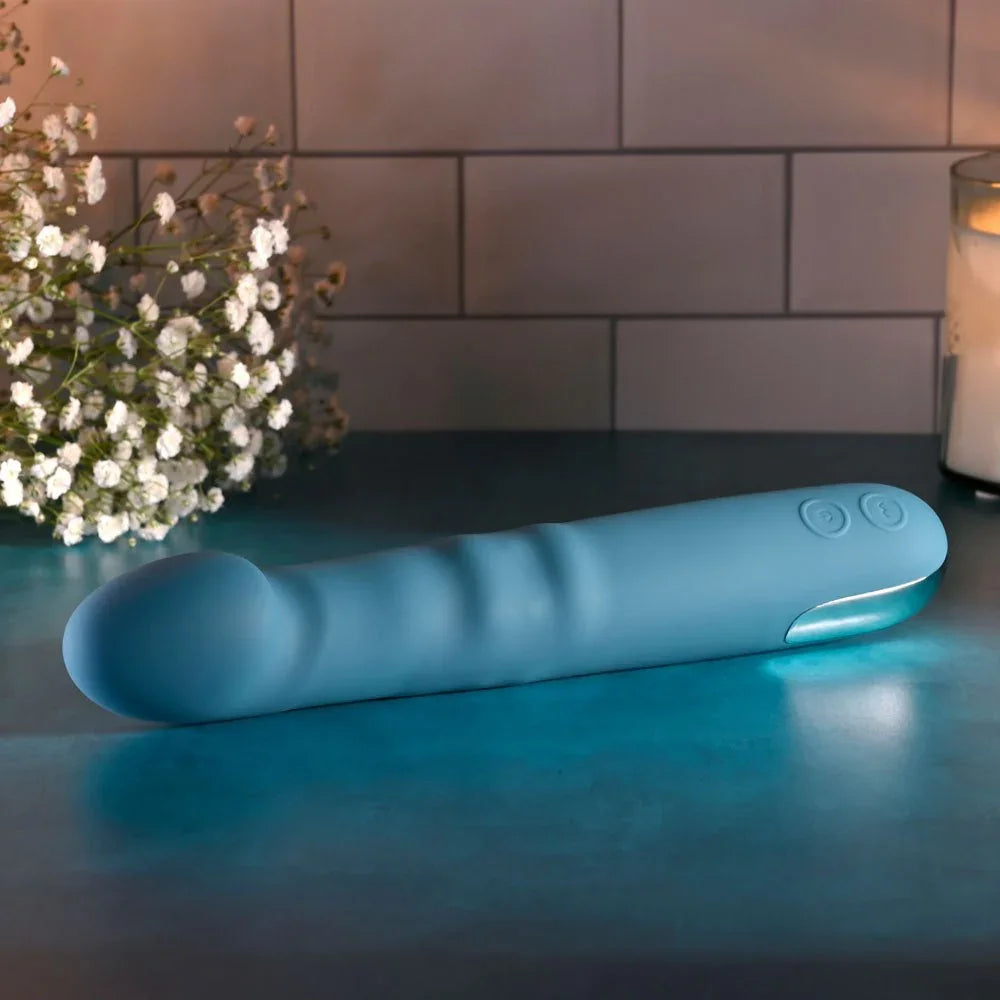 Evolved Queen Of All Trades in teal blue lying flat on a teal surface, tip to the left