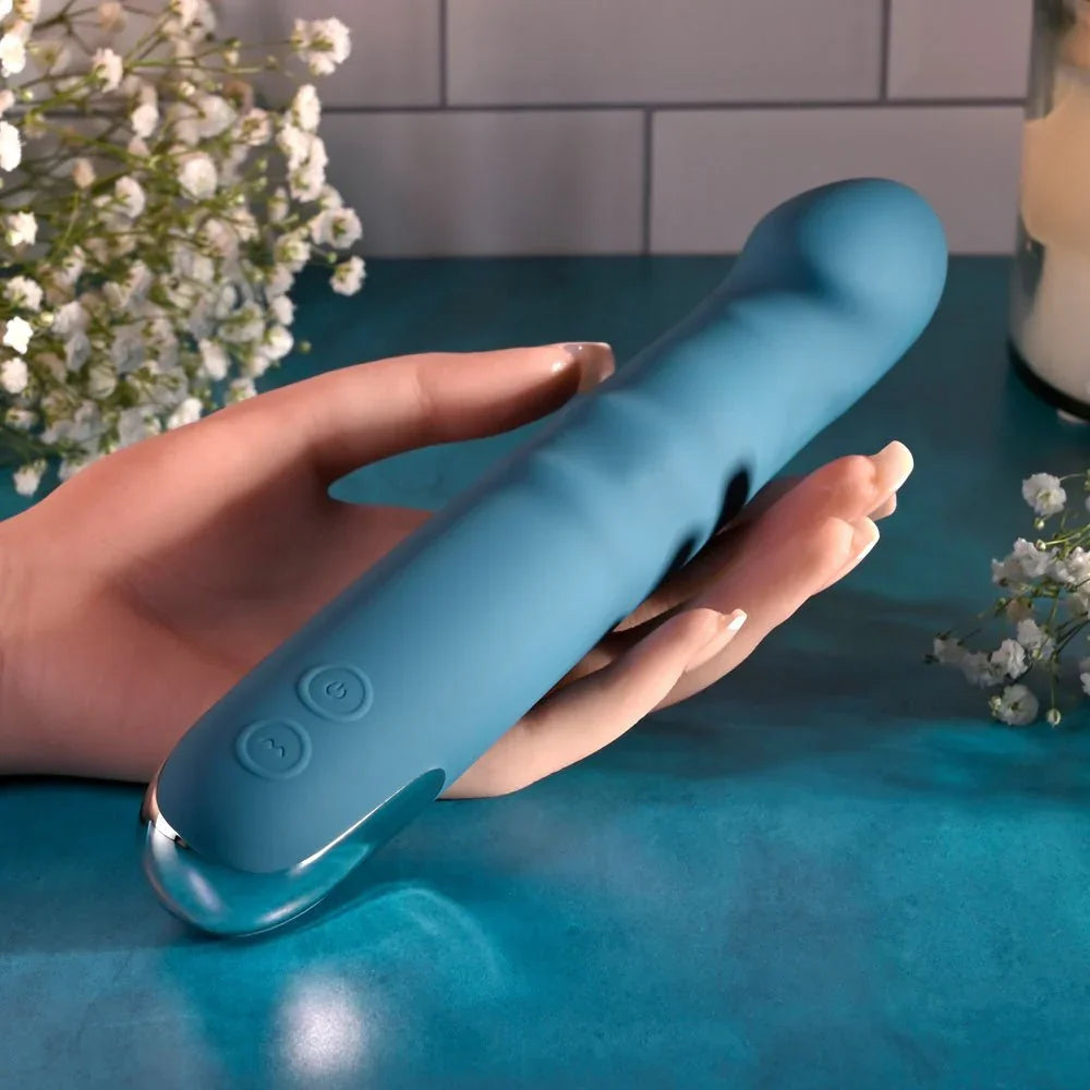 Evolved Queen Of All Trades in teal blue held in an open hand, gypsophila and candle behind