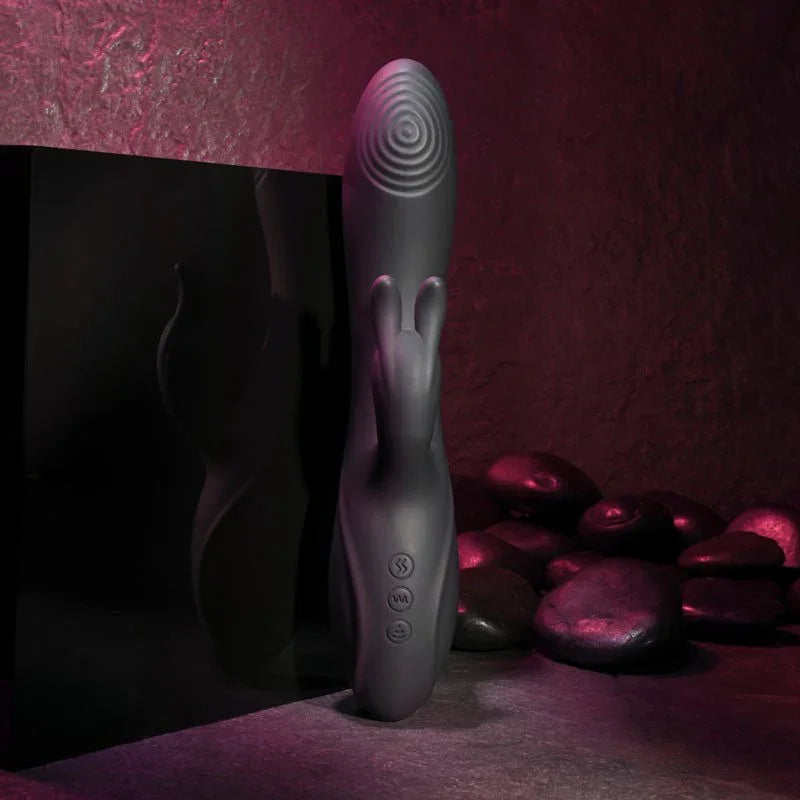 Evolved Rabbit Hole in Black standing upright against a dark panel, river stones behind