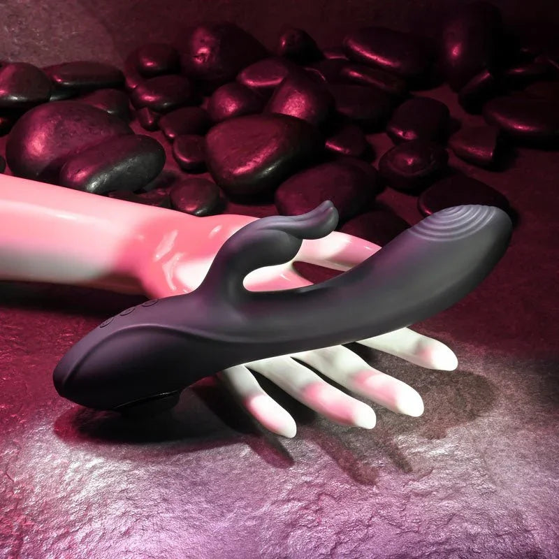 Evolved Rabbit Hole rabbit vibrator in Black lying across a pale mannequin hand, pink lighting