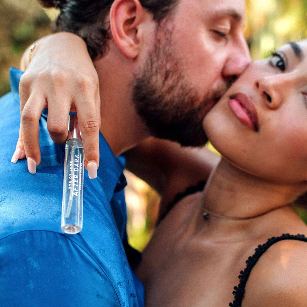 Couple kissing, the woman holding an Eye Of Love After Dark 10ml vial to camera