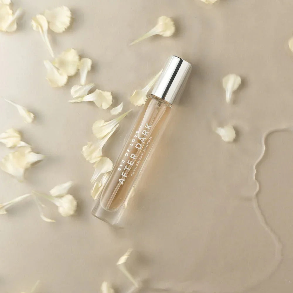 Eye Of Love After Dark 10ml vial lying flat among scattered cream petals