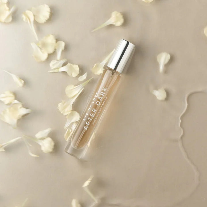 Eye Of Love After Dark 10ml vial lying flat among scattered cream petals