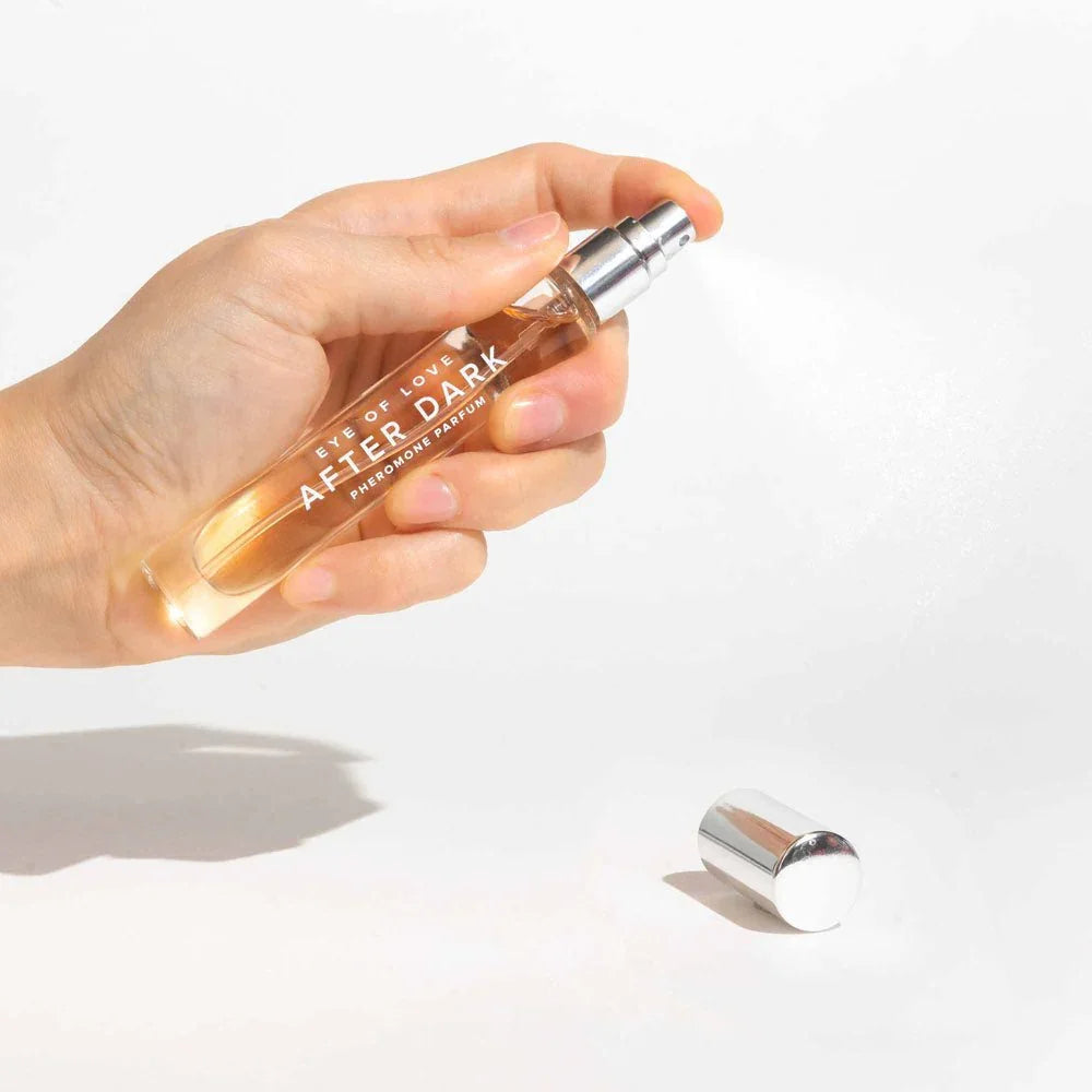 A hand spraying the After Dark 10ml vial, silver cap lying on the white surface