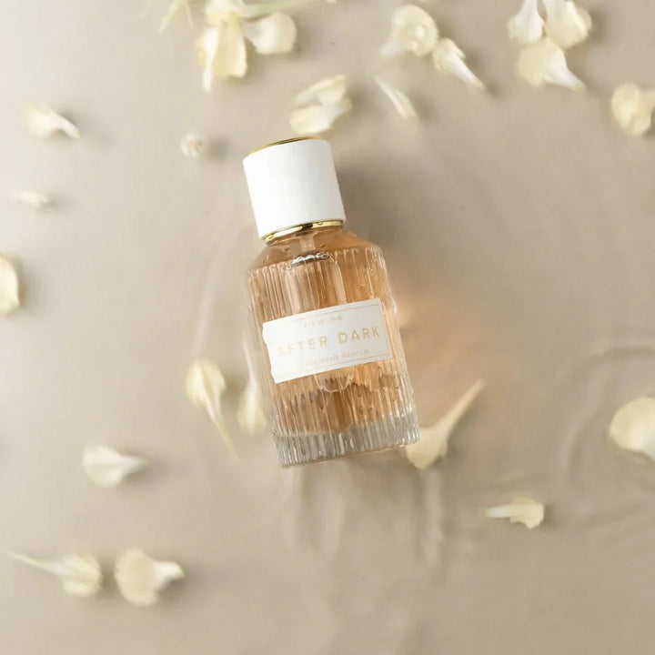 Eye Of Love After Dark 50ml bottle lying flat among scattered pale flower petals