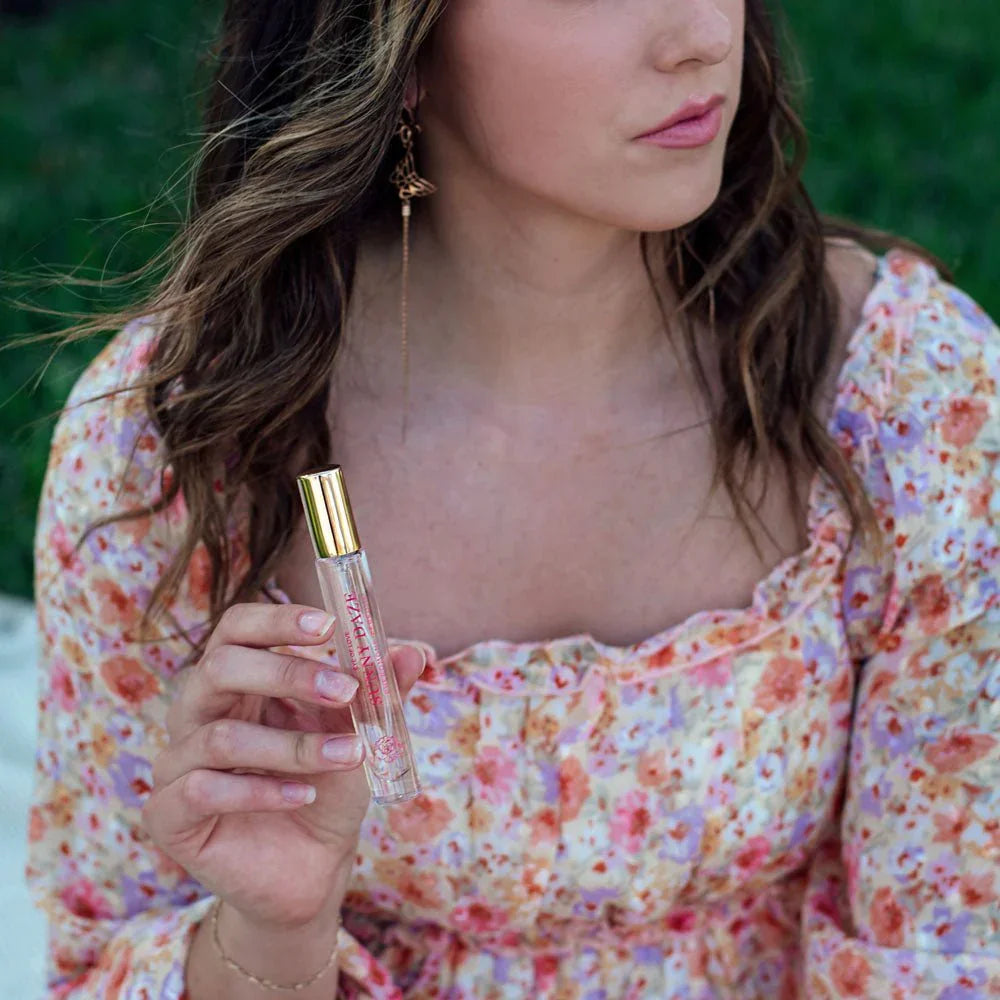 Woman in a floral dress holding the Sunny Daze 10ml vial, garden behind her