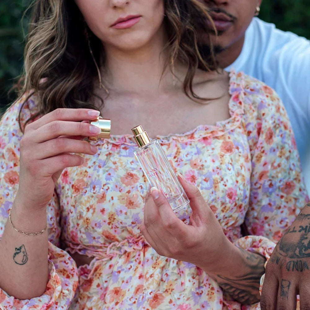 Woman in a floral dress holding the Sunny Daze 30ml bottle, partner behind her