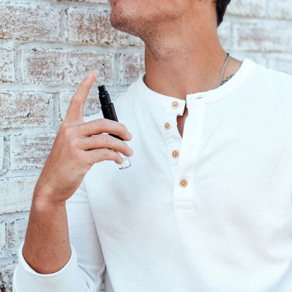 Man in a white henley spraying Eye Of Love Matchmaker Black Diamond LGBTQ Cologne at his neck