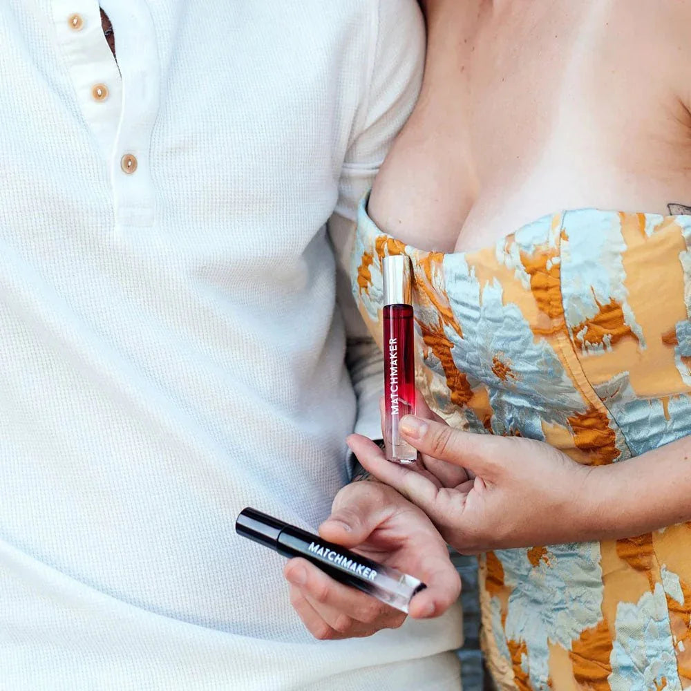 Couple standing close, each holding one Matchmaker Couples Kit vial, red and black