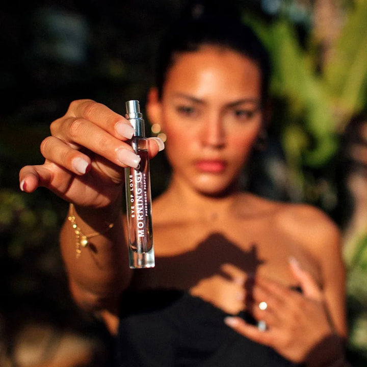 Model in a black top holding the Eye Of Love Morning Glow 10ml vial to camera