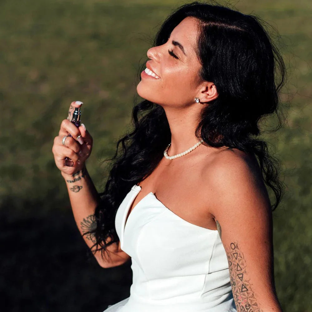 Smiling woman in a white dress spraying the Eye Of Love One Love 10ml perfume