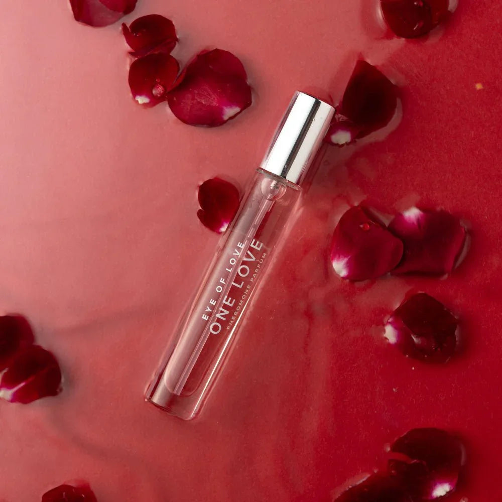 One Love 10ml vial lying in red liquid scattered with dark rose petals
