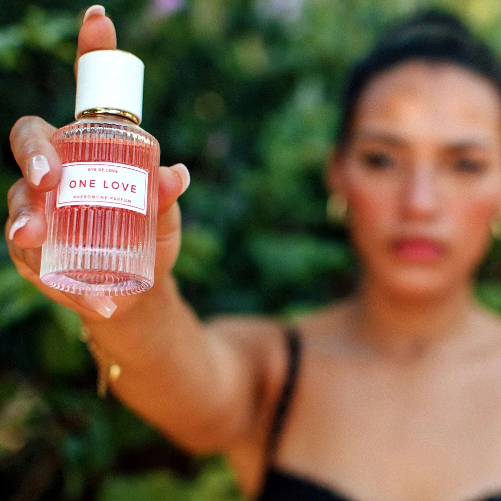 Woman outdoors holding the Eye Of Love One Love bottle out towards the camera