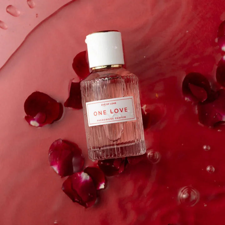 Eye Of Love One Love bottle lying in red liquid scattered with rose petals