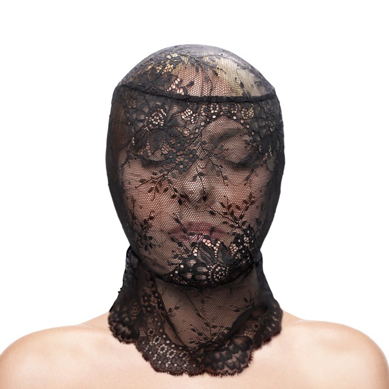 With closed eyes, a person wears the Fetish & Fashion - Lace Hood - Black over their head and shoulders. The form-fitting black lace, with intricate floral patterns, partially obscures their face against a white background that highlights the fabrics details.