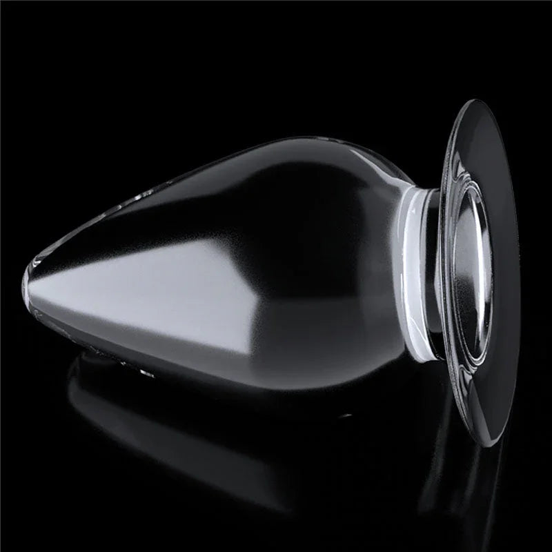 Flawless Clear anal plug lying on its side on a reflective black surface, flared round base
