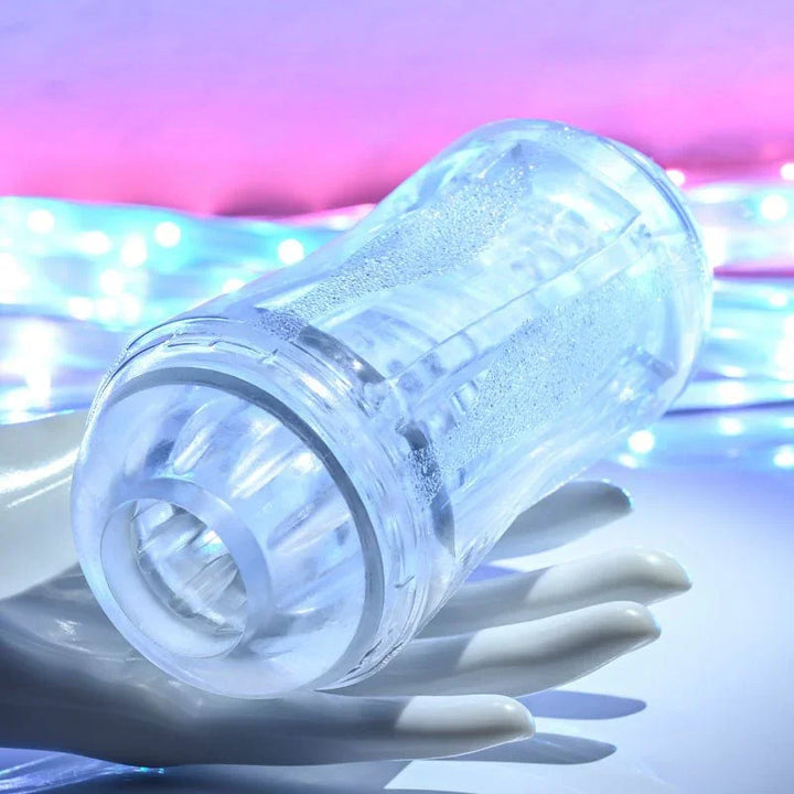 Gender X Double Fantasy stroker in Clear resting on a white mannequin hand, entry facing camera