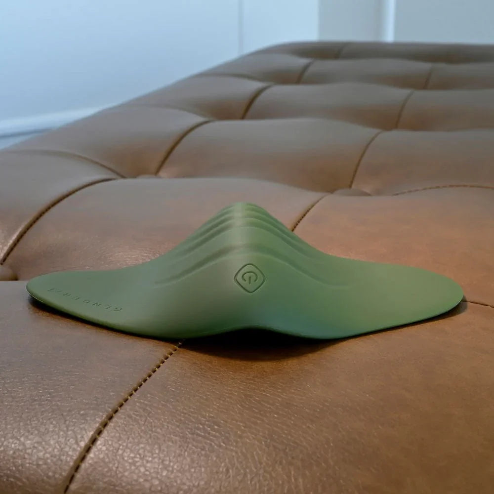 Gender X Pleasure Pad in Green lying flat, low angle showing the raised centre