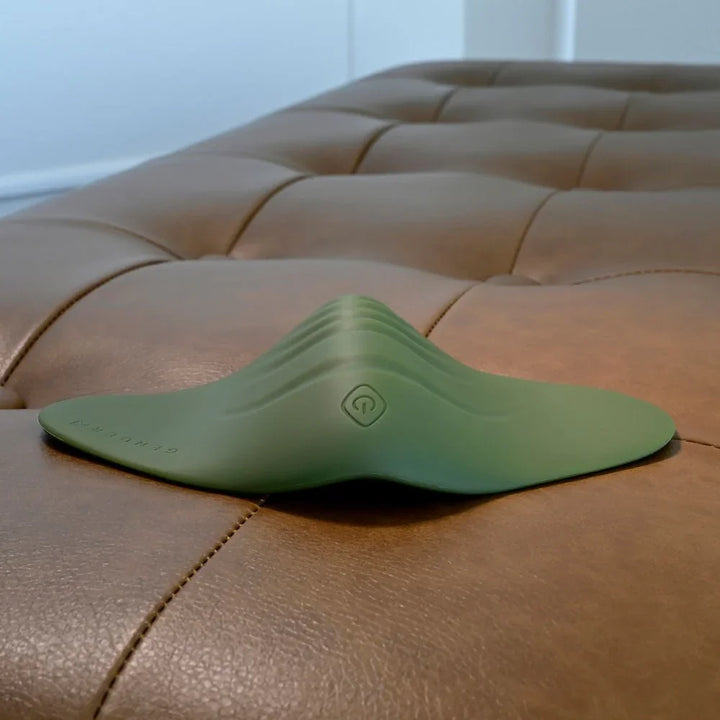 Gender X Pleasure Pad in Green lying flat, low angle showing the raised centre