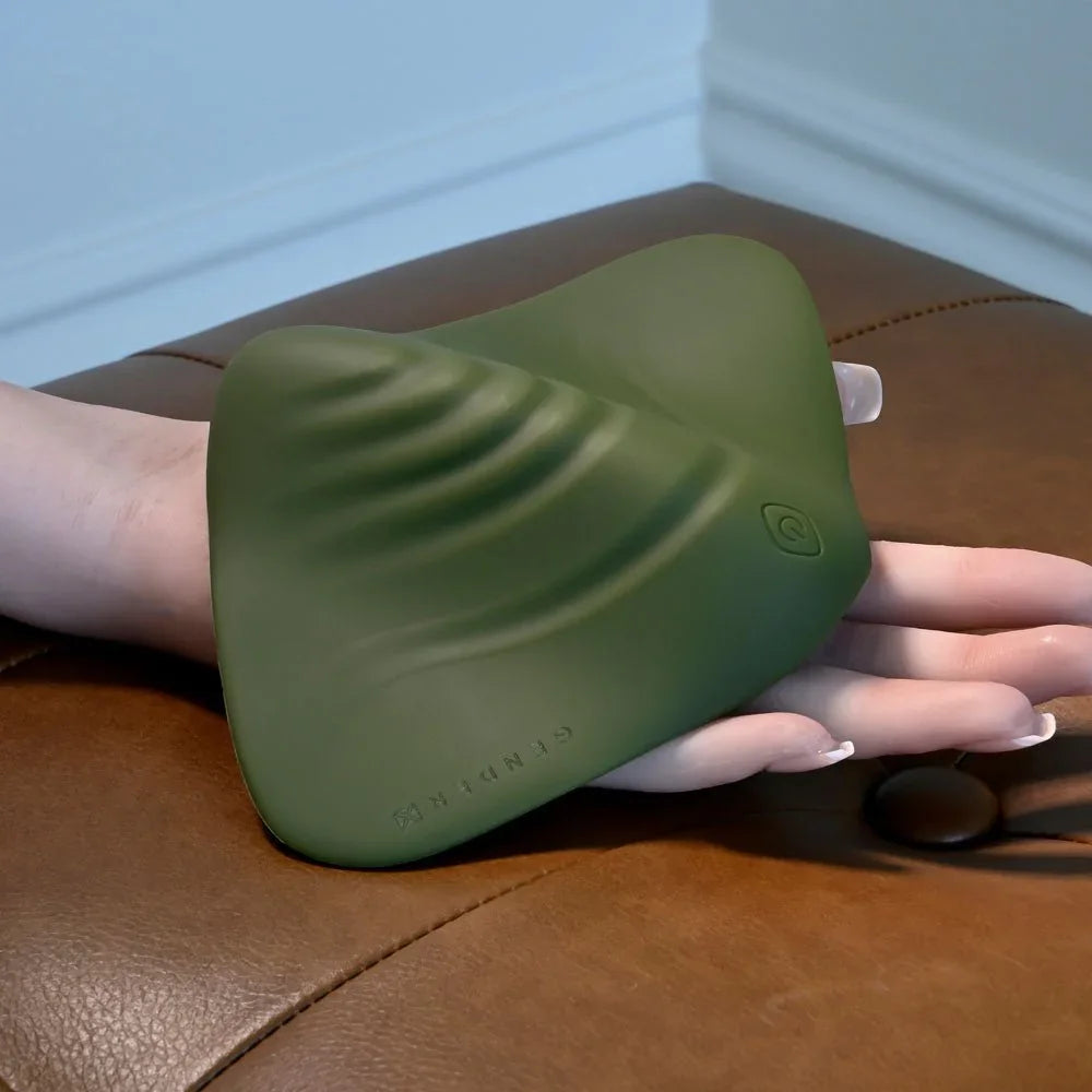 Gender X Pleasure Pad in Green lifted by a hand from the leather ottoman