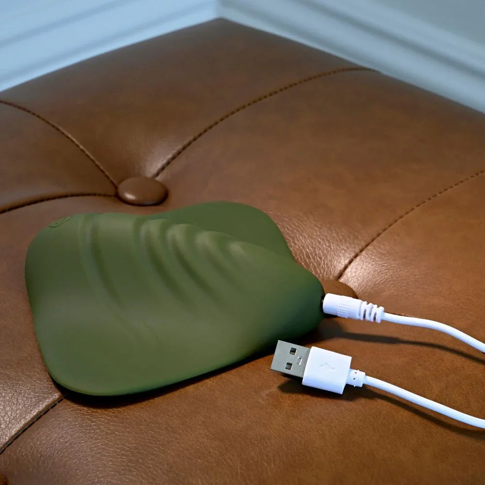 Gender X Pleasure Pad in Green on the ottoman with its USB charging cable plugged in