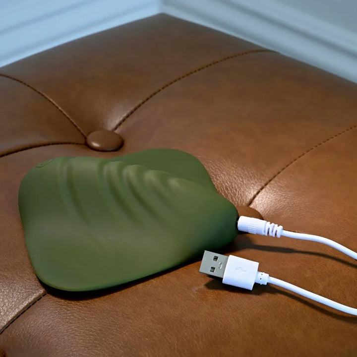 Gender X Pleasure Pad in Green on the ottoman with its USB charging cable plugged in