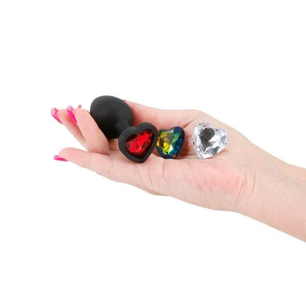 Glams Xchange Heart small plug in Black held in a palm with red, rainbow and clear gems