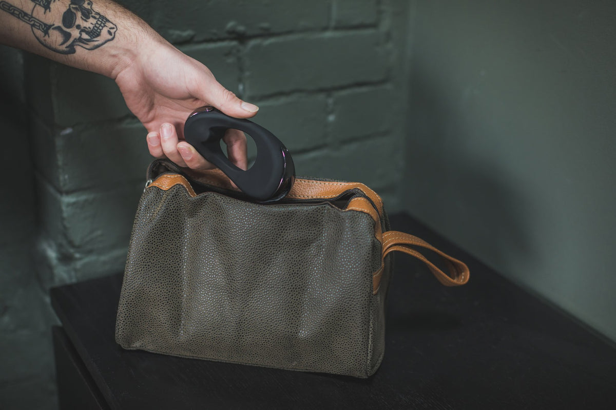 Hand dropping the black Atom Plus into a canvas wash bag
