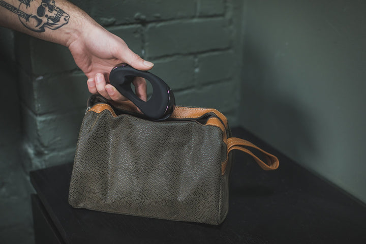 Hand dropping the black Atom Plus into a canvas wash bag
