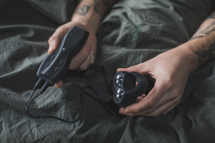 Hot Octopuss Jett with its black remote held in two hands on a bed