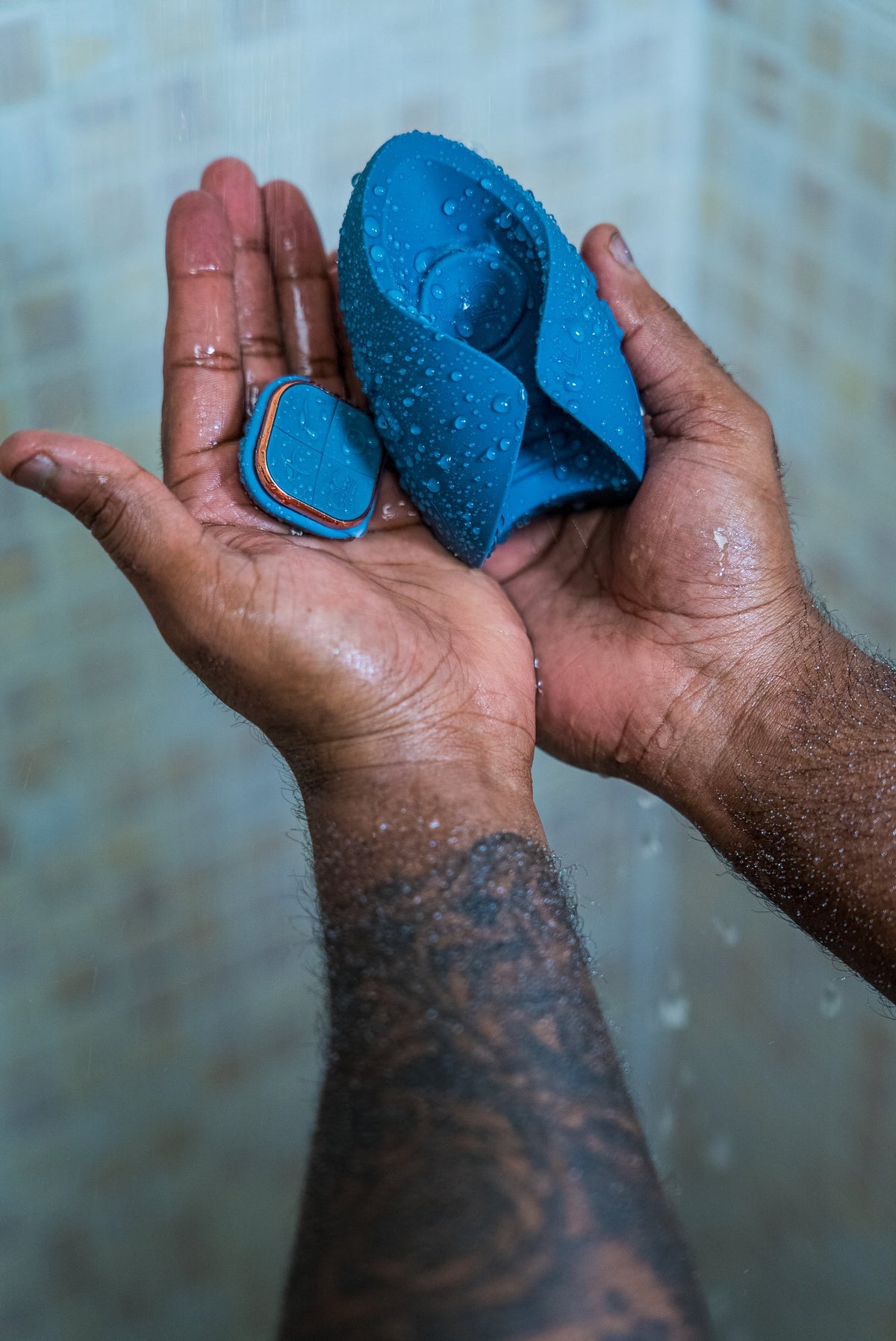 Wet hands holding the blue Pulse Duo and its remote