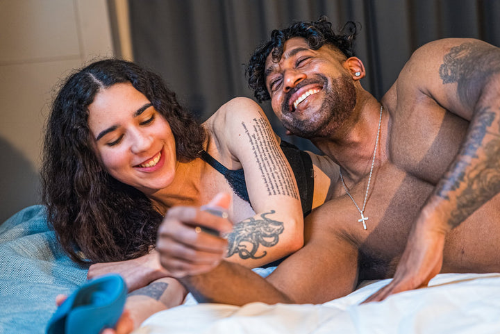Laughing couple on a bed, the blue Pulse Duo in the foreground