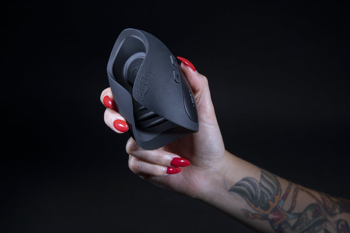 Hand with red nails holding the Pulse Solo Essential on a dark backdrop