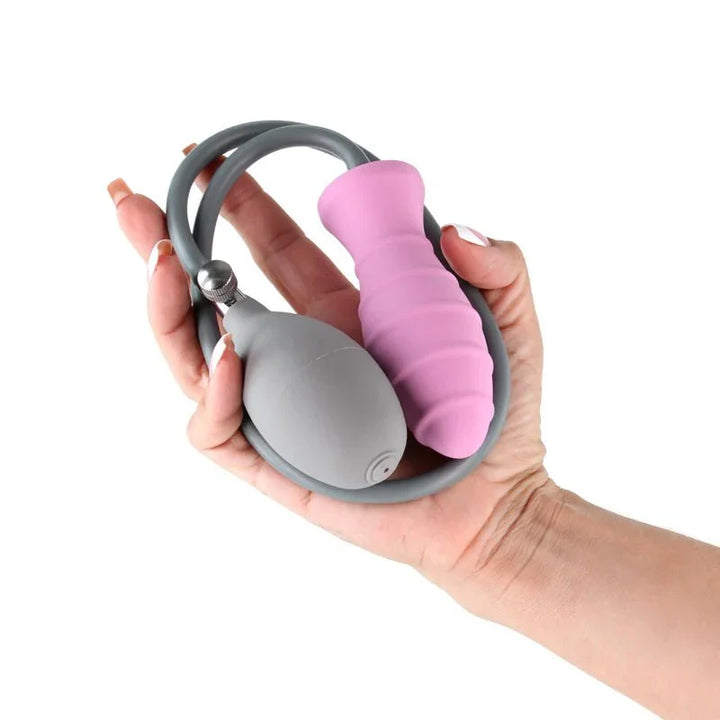 INYA InflataPlay inflatable plug in Pink held in a hand with its pump bulb and hose