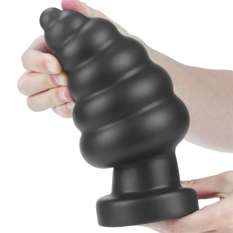 Hand gripping the black ribbed Anal Cracker plug, showing its bulk against the palm