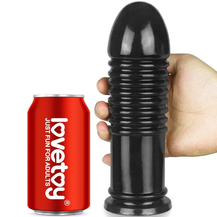 Hand holding the black Anal Bumper beside a soft drink can for scale