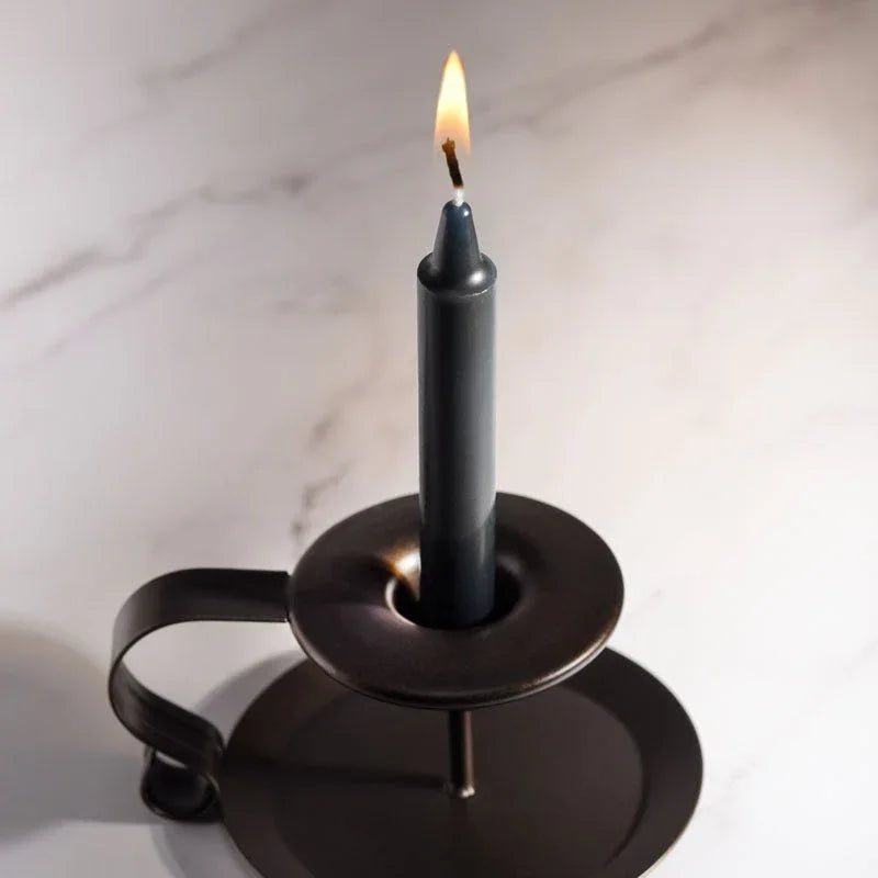 LaCire black drip candle burning in a metal holder on a marble surface