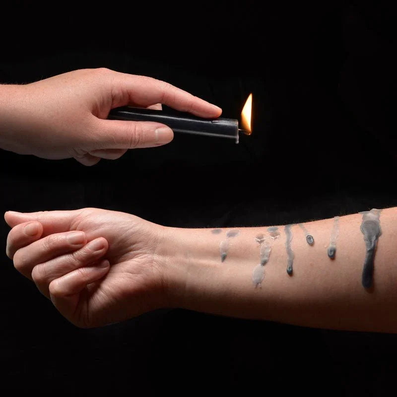 Lit LaCire black drip candle dripping wax onto a forearm
