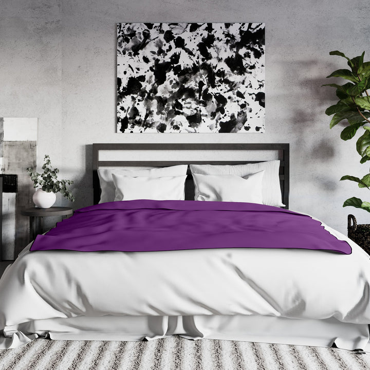 Purple Fascinator throw draped across the foot of a made bed in a bedroom