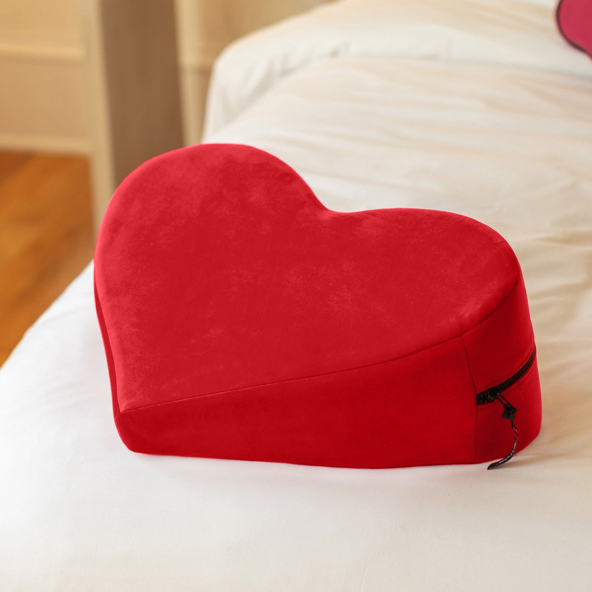 Red Heart Wedge resting on a white bed, showing its sloped side and zip