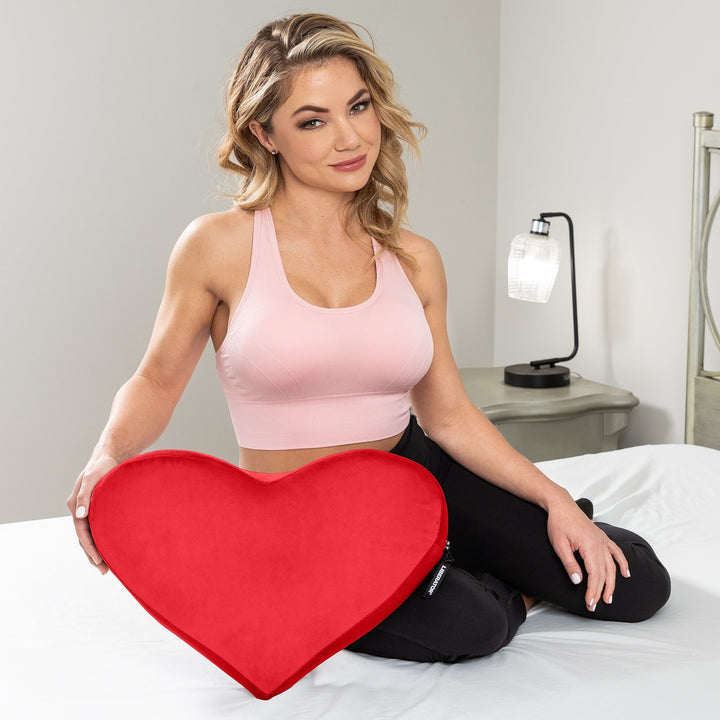 Smiling woman in a pink sports top holding the red Heart Wedge on her lap