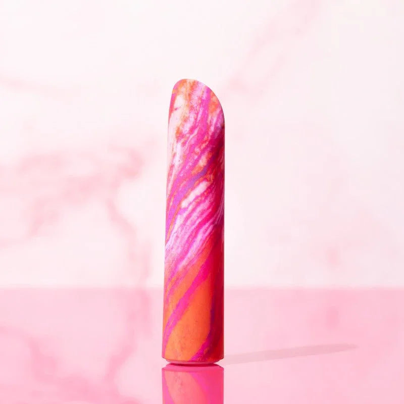 Coral Fiery bullet standing upright against a pink marble backdrop