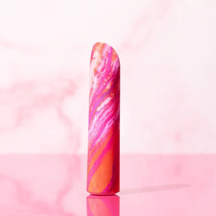 Coral Fiery bullet standing upright against a pink marble backdrop