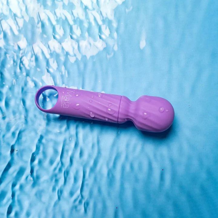 Maia Dolly mini wand in Purple lying in shallow water, showing it is submersible