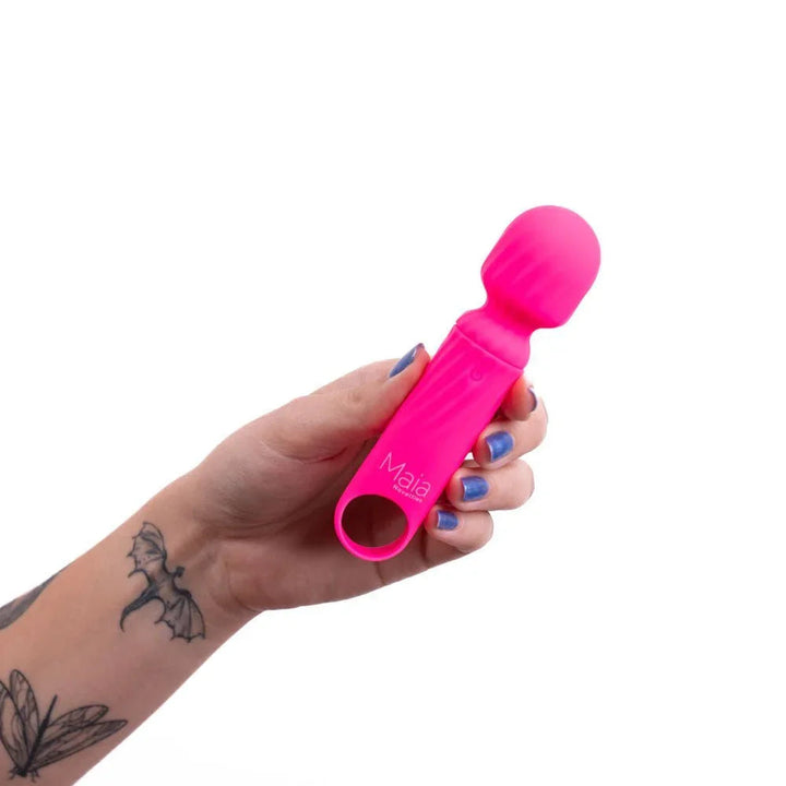Maia Dolly mini wand in Pink held in a tattooed hand, showing its scale
