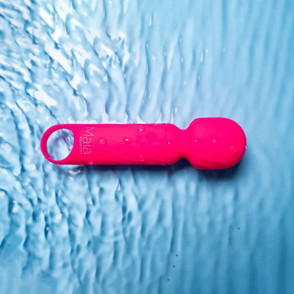 Maia Dolly mini wand in Pink lying in shallow water, showing it is submersible