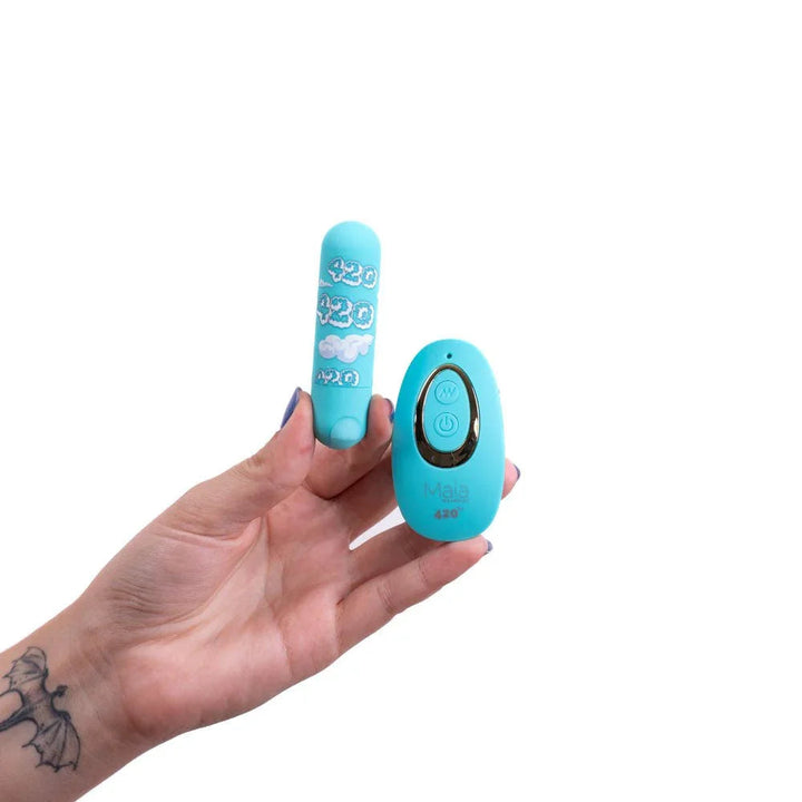 Maia Jessi 420 cloud-print bullet and teal remote held in a tattooed hand